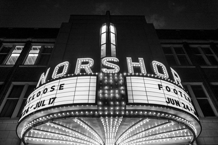 Black and white photo of the NorShor Theatre marquee lit up, displaying Footloose and date ranges.