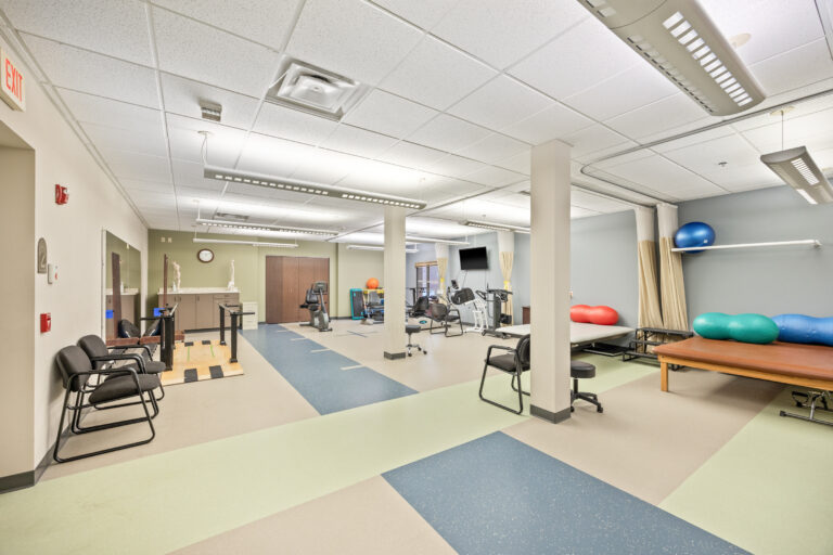 A rehab therapy room in The Fountains with exercise equipment, balance balls, and therapy beds.