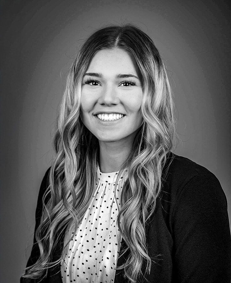 Abby Weber, a smiling women with long wavy hair and a polka-dot blouse.