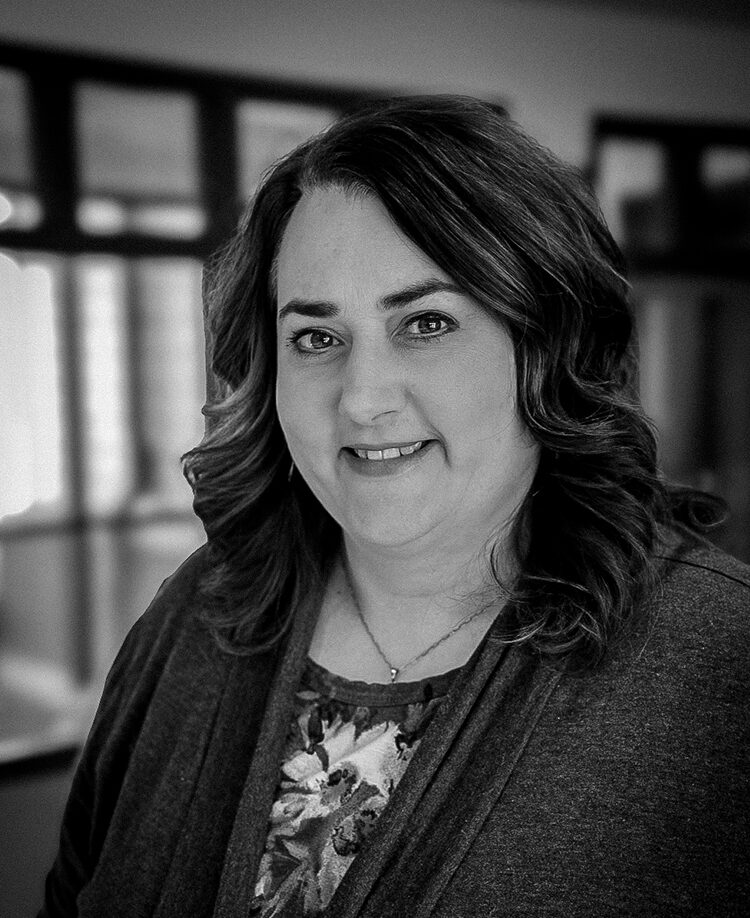 Brenda Turner, a woman with wavy hair, smiles at the camera in a well-lit indoor setting.