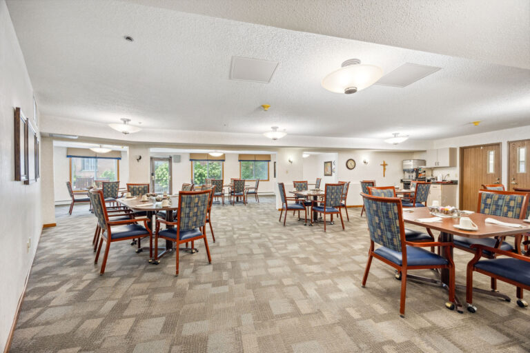 Benedict Court Dining: A bright room with wooden tables, chairs, place settings, wall art, and overhead lighting.
