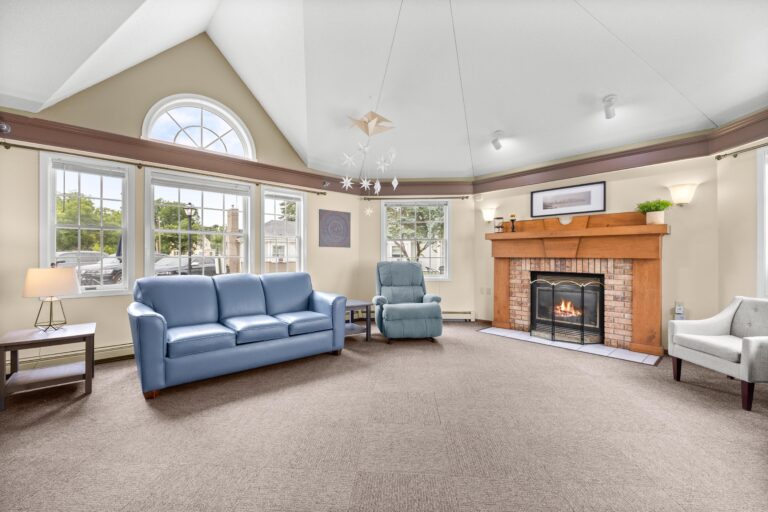Spacious living room with blue chairs, a fireplace, and large windows letting in natural light.