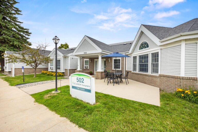 Single-story white building with patio seating, a sign reading 502, and a clear, sunny sky.