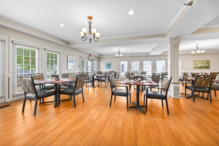 Bright, spacious dining room with neatly set tables, wooden floors, and large windows letting in natural light.