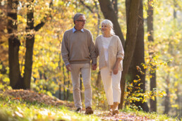 senior couple walking through the woods hand-in-hand in the Fall talking about what legacy they'd like to leave.
