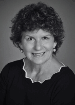Black and white portrait of Margene Reno. She wears ear rings and a dark sweater blouse with white trim at the collar.