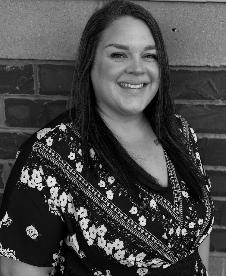 Black and white portrait of Michelle O'Connor. She wears a dark, short-sleeve blouse with a floral print.