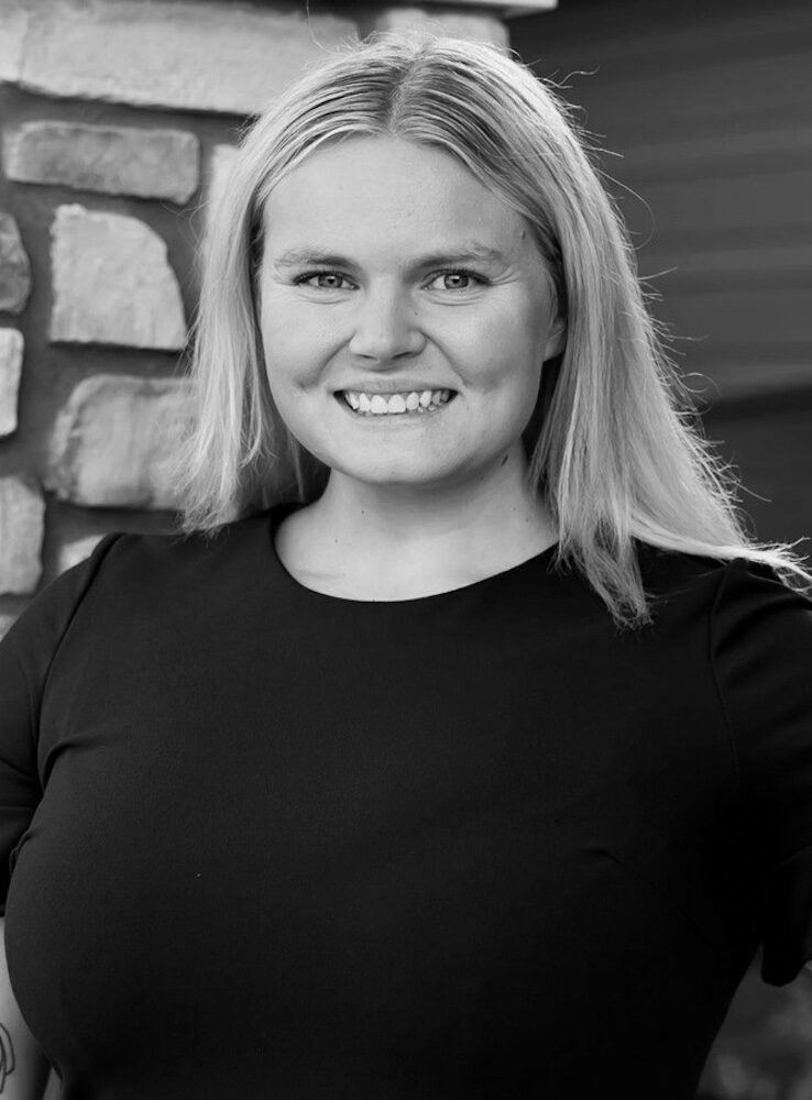 Black and white portrait of Abby Moore. She wears a dark t-shirt.