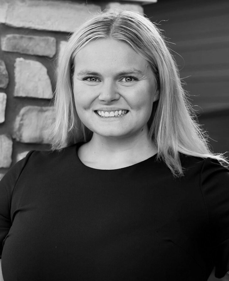 Black and white portrait of Abby Moore. She wears a dark t-shirt.