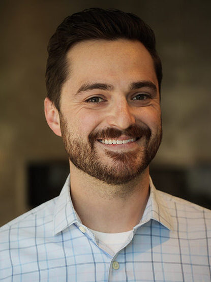 Portrait of Brandyn Liebe with short brown hair, short brown beard and mustache, wearing a button-up collar shirt.