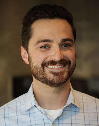 Portrait of Brandyn Liebe with short brown hair, short brown beard and mustache, wearing a button-up collar shirt.
