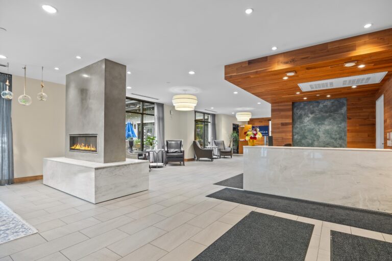 Modern lobby with a marble fireplace, reception desk, and seating area with armchairs.
