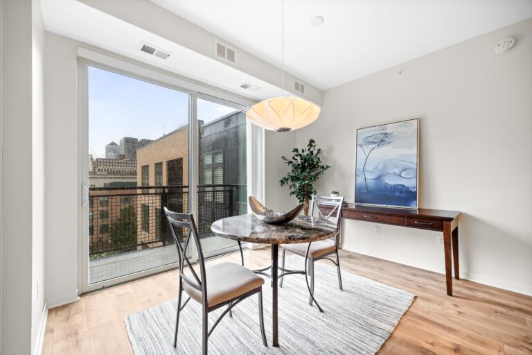 Modern dining area with round table, two chairs, large window, and contemporary decor.