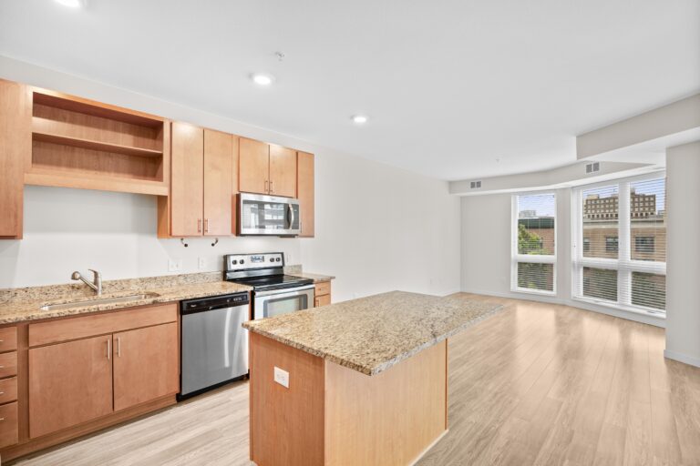 Modern kitchen with wood cabinets, granite countertops, stainless steel appliances, and large windows.