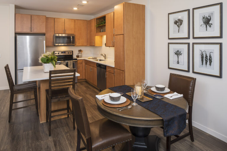 Modern kitchen and dining area with wooden cabinets, round table, and framed art on the wall.