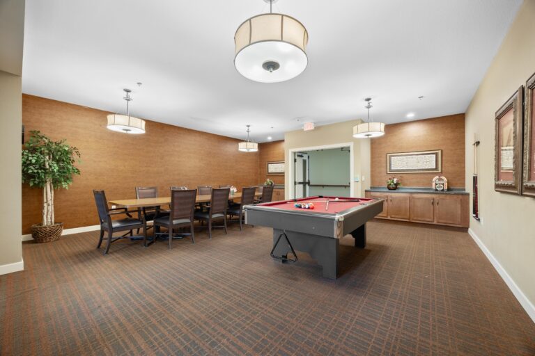 Room with a pool table, dining table with chairs, wall art, ceiling lights, and a potted plant.