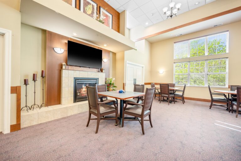 Modern dining area with tables, chairs, a fireplace, large windows, and bright natural light.