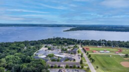 Aerial view of a school campus near a large lake with a running track and sports fields.