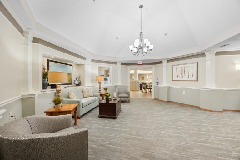 Bright, spacious lounge with sofas, armchairs, lamps, and a chandelier in a modern common area.