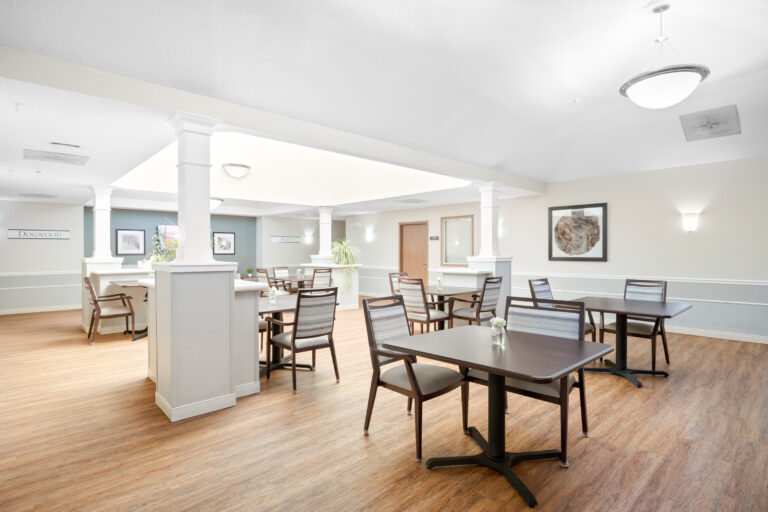 Bright, modern dining area with wooden floors, several tables and chairs, and framed art on the walls.