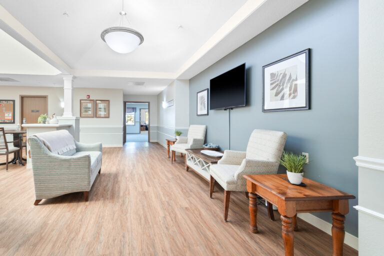 Modern lounge with chairs, a sofa, a TV, framed art, and wood flooring.