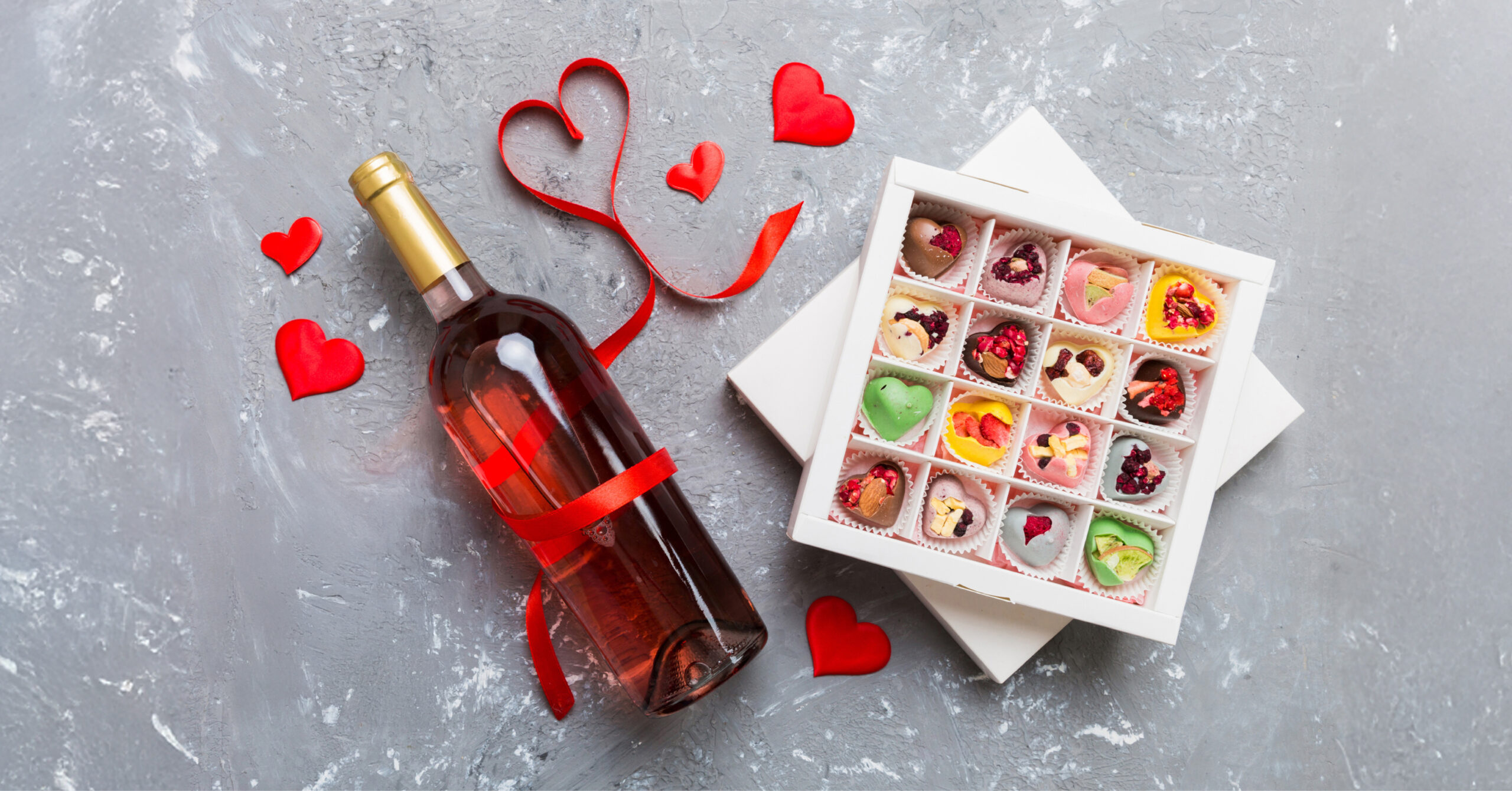 bottle of wine next to a box of heart-shaped chocolates