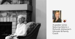 Black and white photo of an elderly woman with glasses sitting in a comfortable chair in a living room next to a stone fireplace, smiling and relaxed.