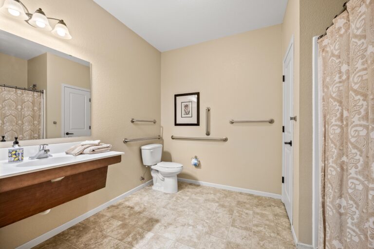 Large cream colored bathroom with white fixtures, sink, vanity and shower with fabric curtain.