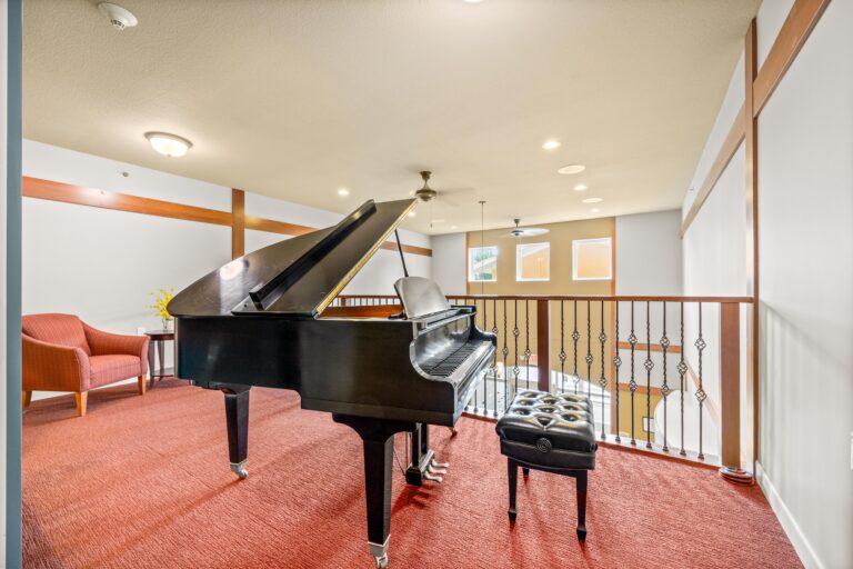 Black baby grand piano in a sitting area at the railing overlooking an atrium.