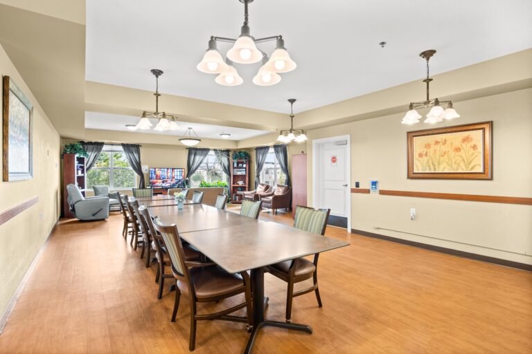 A bright room with chandeliers above dining tables and chairs.