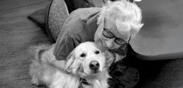 A senior woman smiling and hugging a golden retriever volunteer named Bella. Bella’s visits bring comfort and smiles!