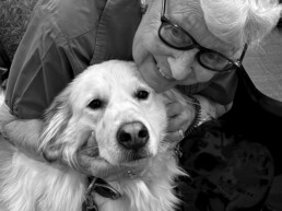 A senior woman smiling and hugging a golden retriever volunteer named Bella. Bella’s visits bring comfort and smiles!