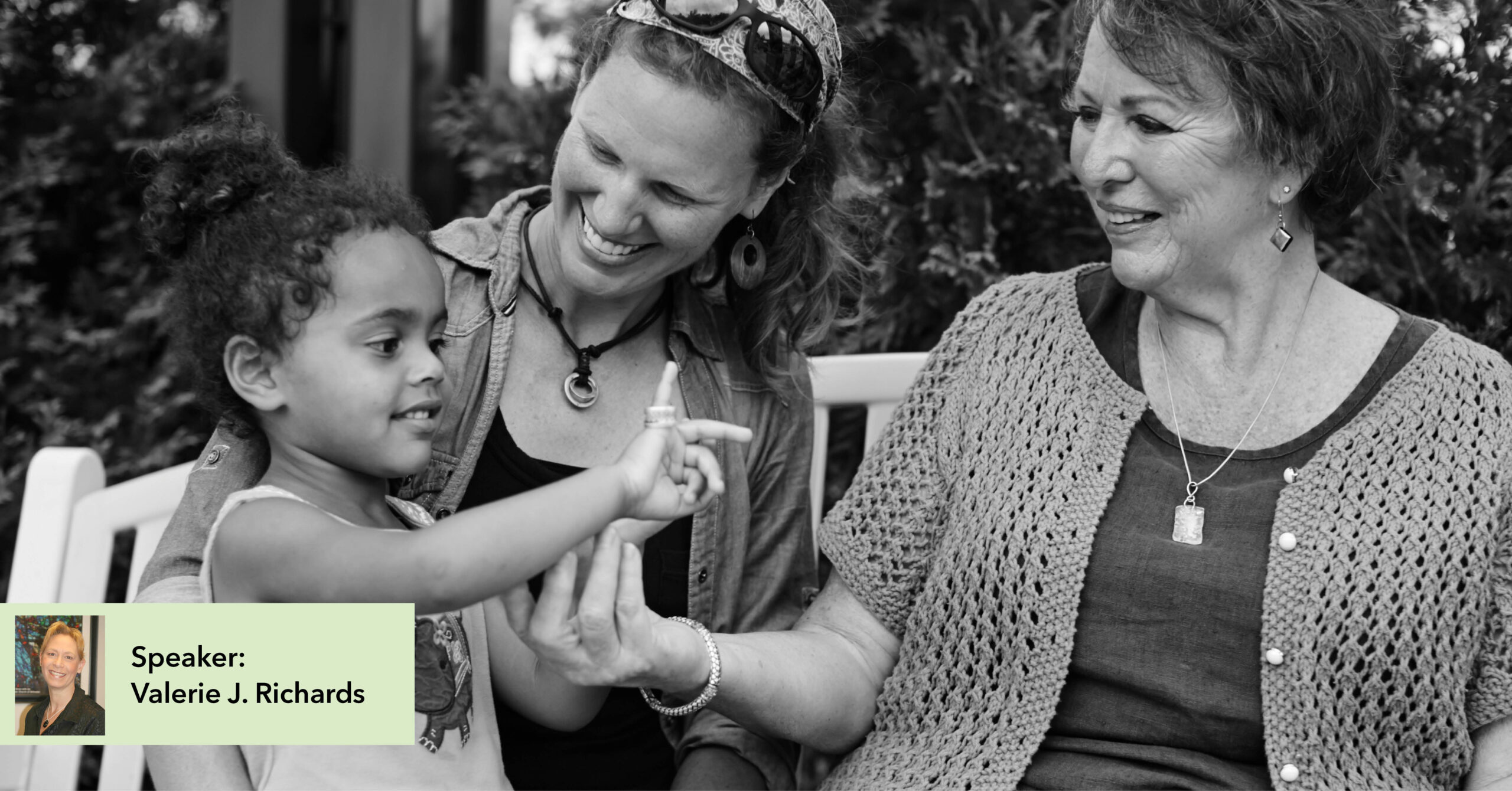 Three people sit on a bench outdoors. A child and two adults share a joyful moment. They display happiness and connection in a natural setting.