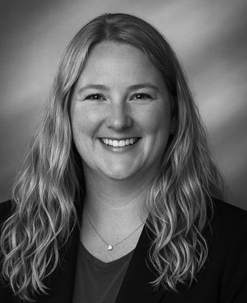 Professional black and white portrait of Jennifer Trevillion, wearing a dark sweater, jacket and necklace