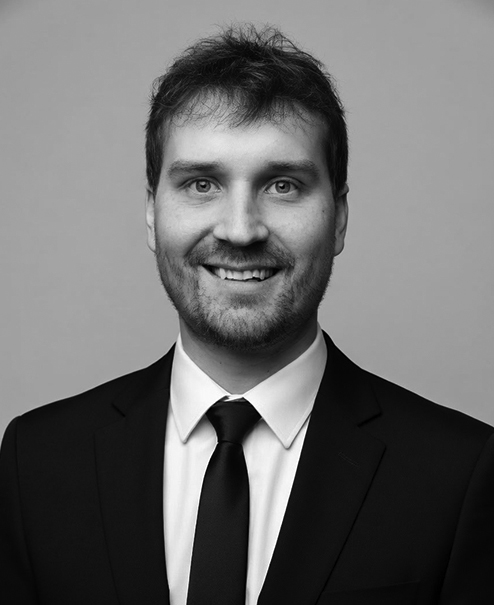 Professional black and white portrait of Justin Boldt wearing a jacket and tie