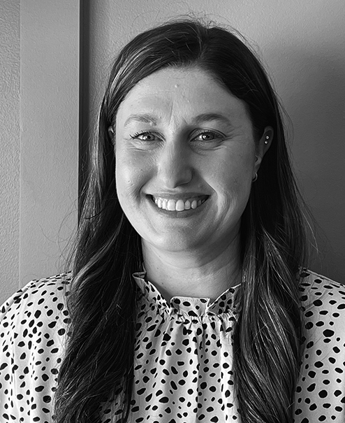 Professional black and white portrait of MacKenzie McVay, wearing a light-colored blouse with dark polka dots