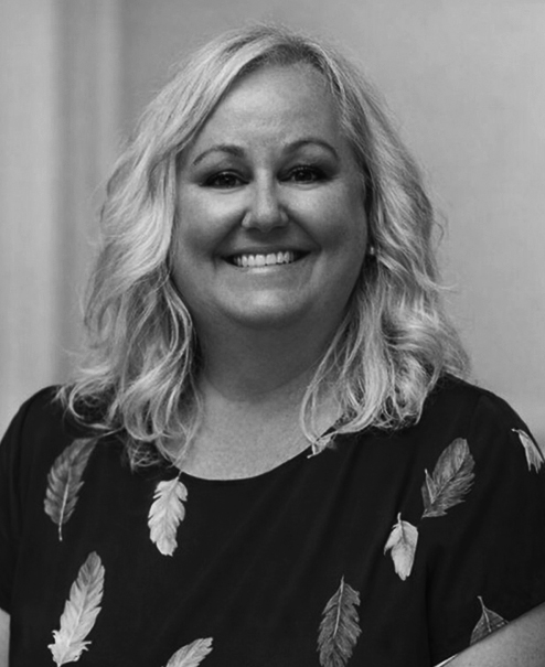 Professional black and white portrait of Molly DeFrance, wearing a dark short-sleeve blouse with feather print