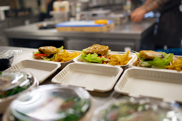 Three meals placed in open compostable take-out containers ready to go.