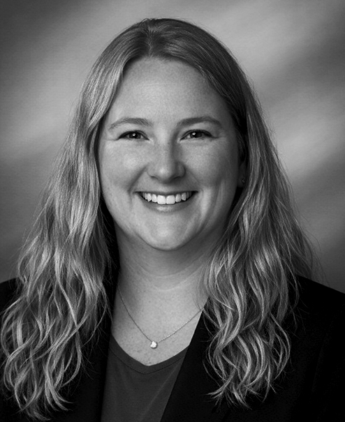 Professional black and white portrait of Jennifer Trevillion, wearing a dark sweater, jacket and necklace