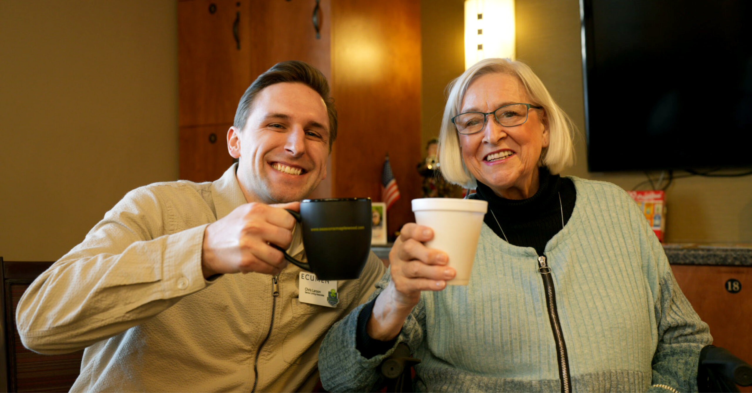 Smiling man and woman holding mugs in a cozy setting.