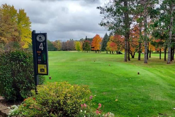 View of a fairway in fall lined by old-growth trees that are changing color.