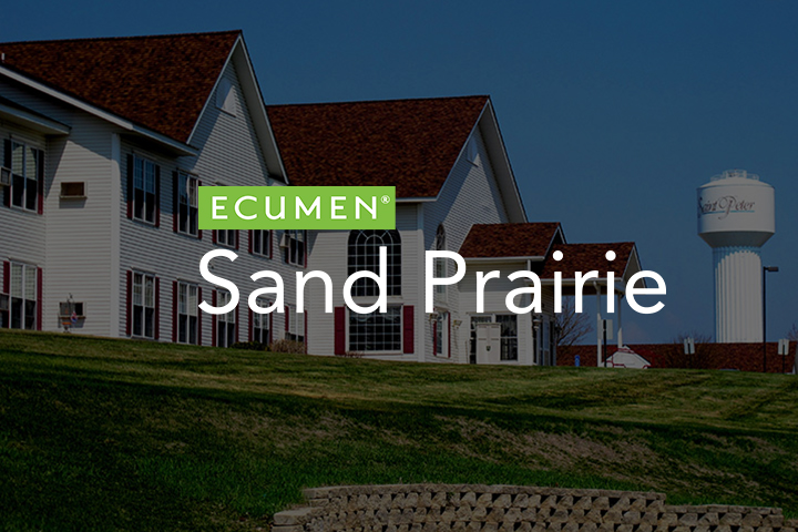 Ecumen Sand Prairie logo overlayed on a photo of the Sand Prairie building with a water tower in the background