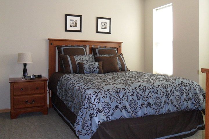 A furnished apartment bedroom with a large window letting in lots of natural light