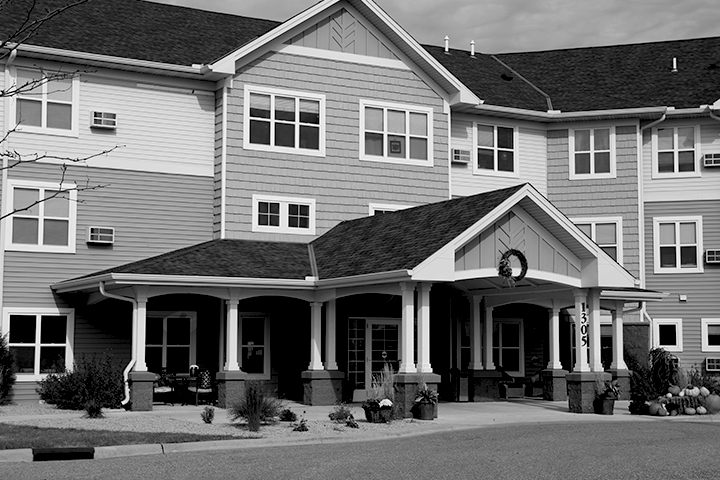 Black and white photo of the main entrance of a three-story apartment building, featuring a large portico