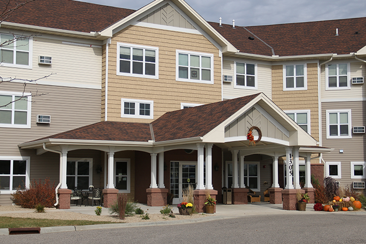 Main entrance of a three-story apartment building, featuring a large portico