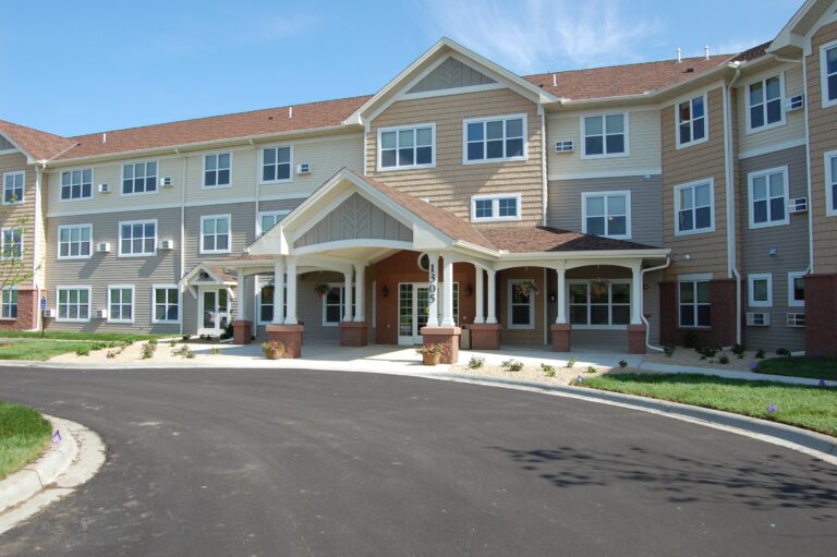 Main driveway and entrance of a three-story apartment building, featuring a large portico