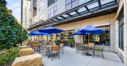 An outdoor restaurant patio with blue umbrellas and tables outside Abiitan Mill City