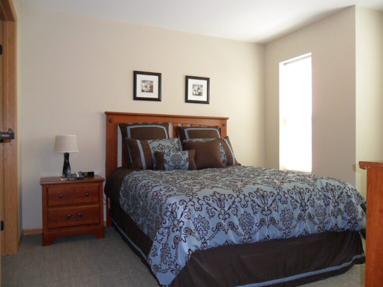 A furnished apartment bedroom with a large window letting in lots of natural light