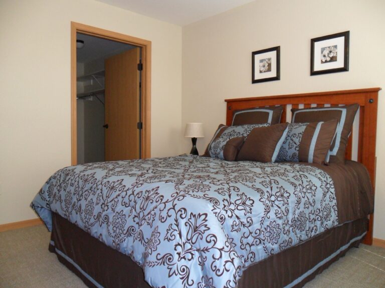 A furnished apartment bedroom with a large window letting in lots of natural light
