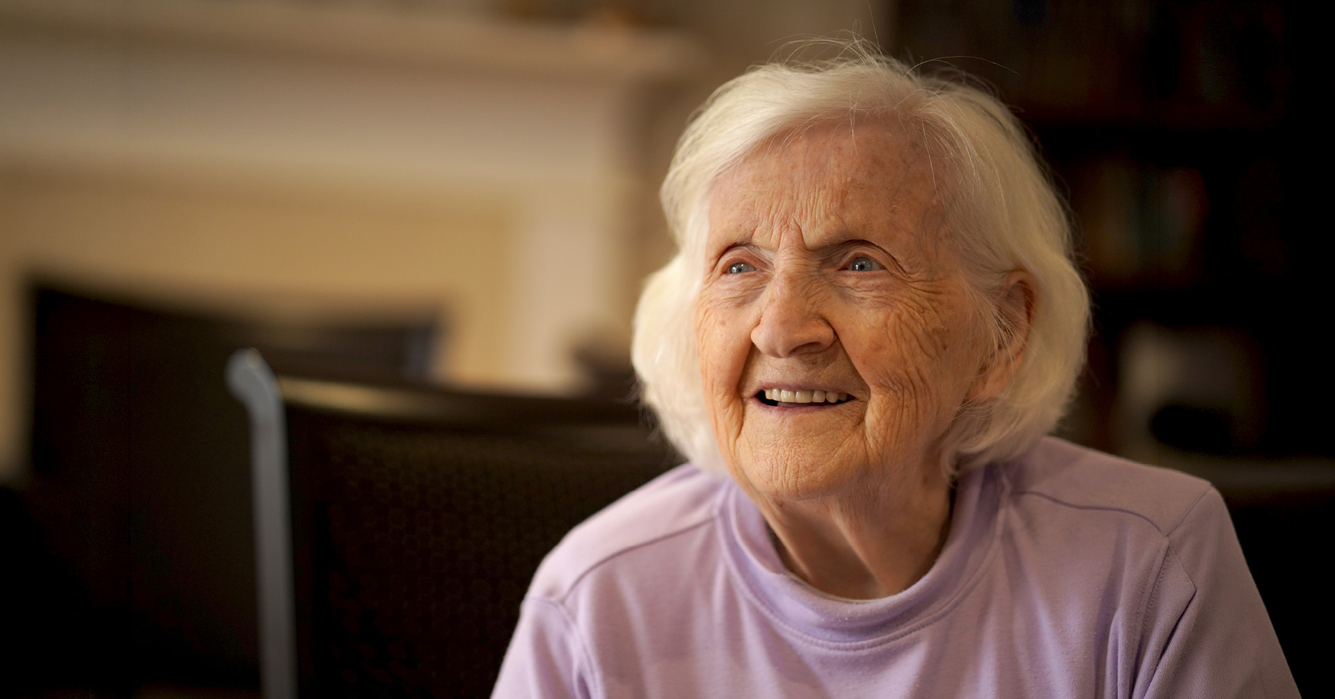 An elderly woman with white hair smiles